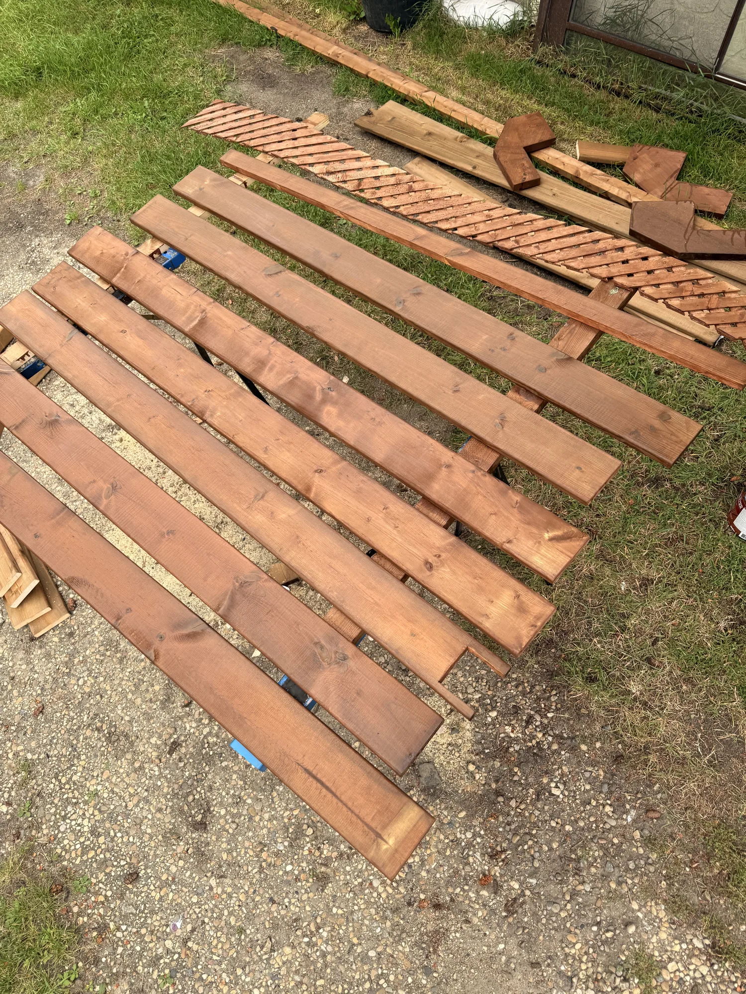 Boards part-stained on the grass, the colour change obvious