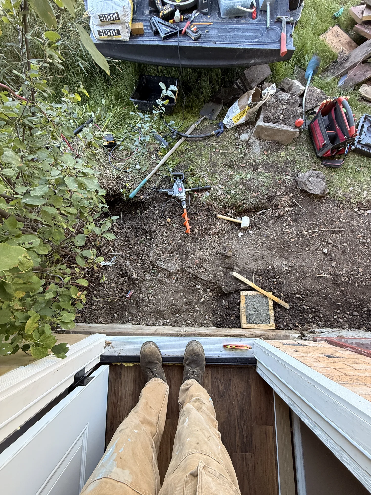 Looking down from the open front door at the bare ground below