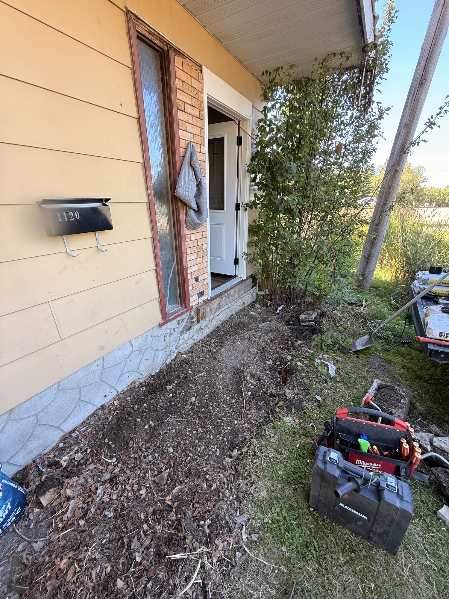 The porch stripped out, back to bare dirt beside the house