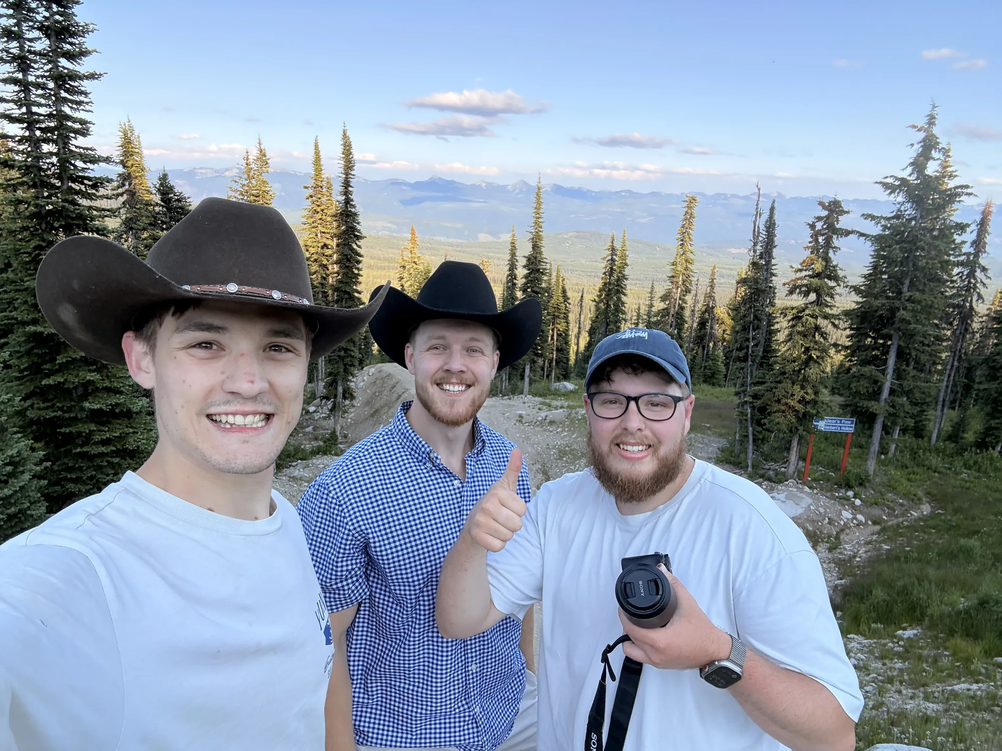 Three of us in cowboy hats at Big White, forest and valley behind