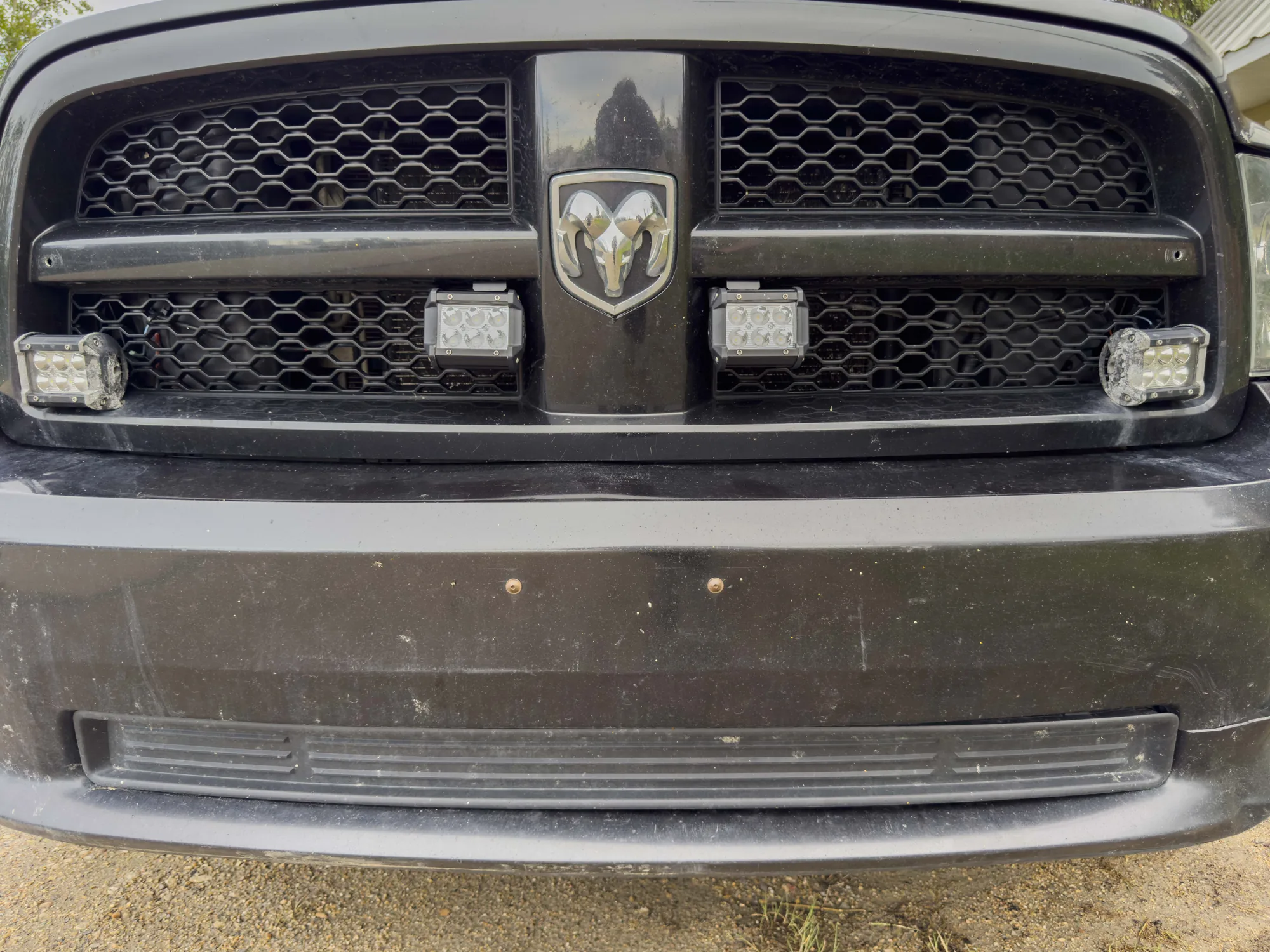 Four LED pod lights mounted in the lower grille of a black RAM 1500