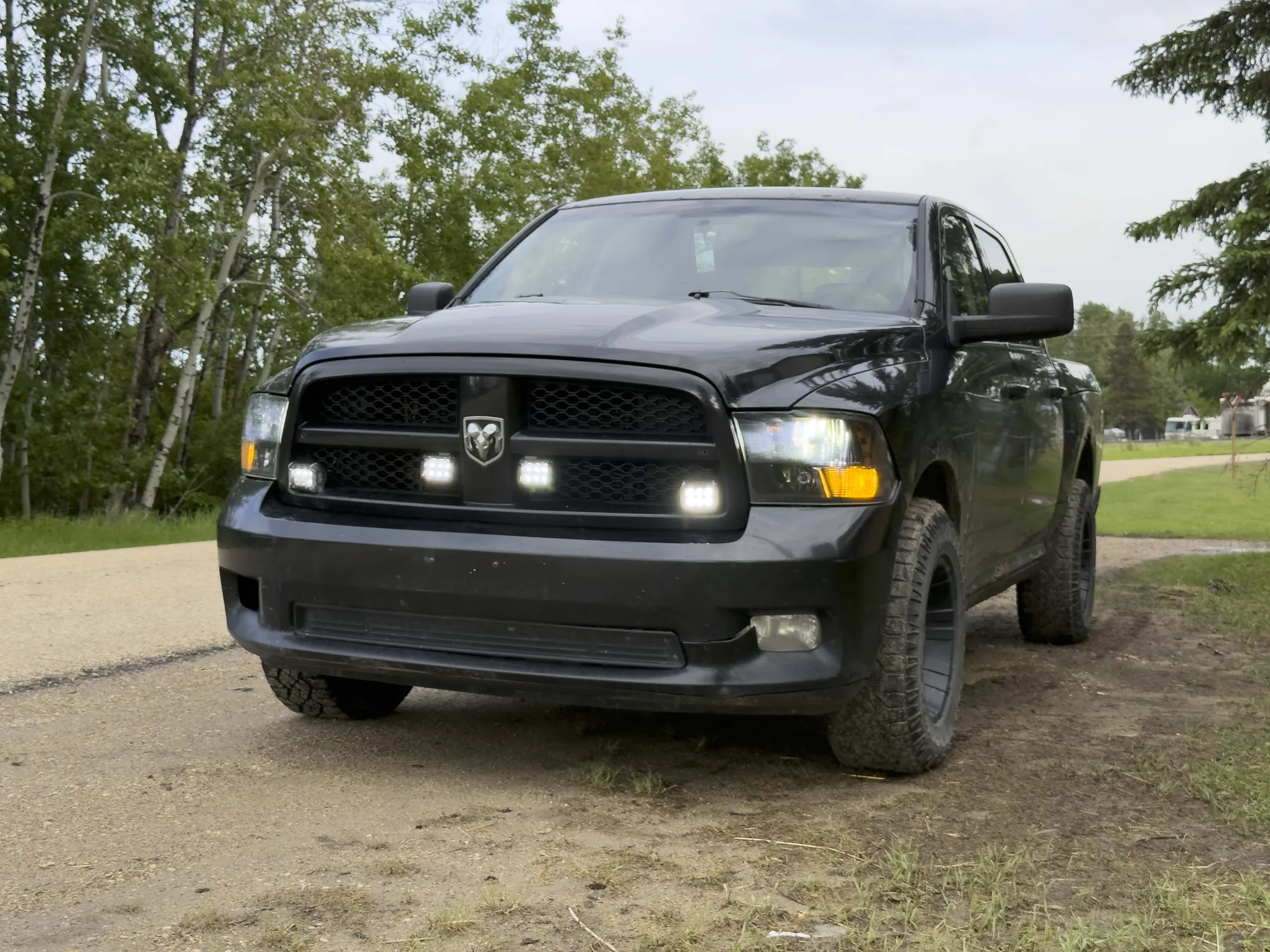 A black RAM 1500 on a gravel campground road showing its all-terrain tyres
